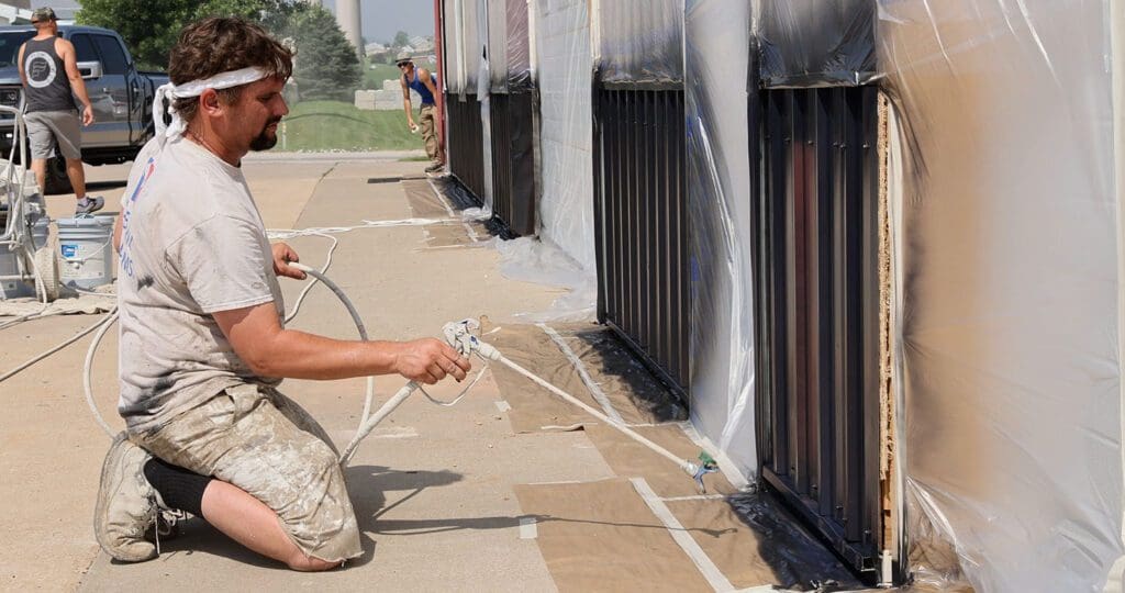 Painter spray painting sections of a commercial building