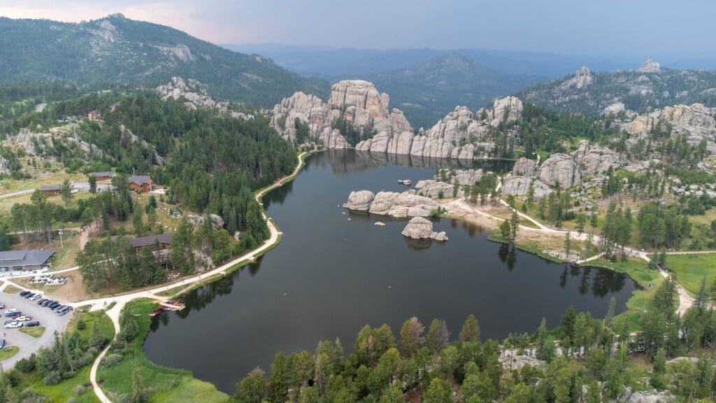 Aerial view of Sylvan Lake in Custer, SD, surrounded by granite rock formations and dense pine forest, showcasing the natural beauty and scenic landscape of the Black Hills.