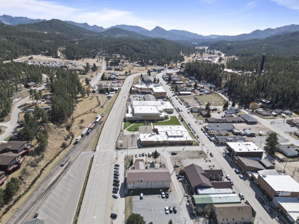 Aerial view of downtown Hill City, SD with the 1880 Train tracks and depot, surrounding businesses, and scenic Black Hills landscape.